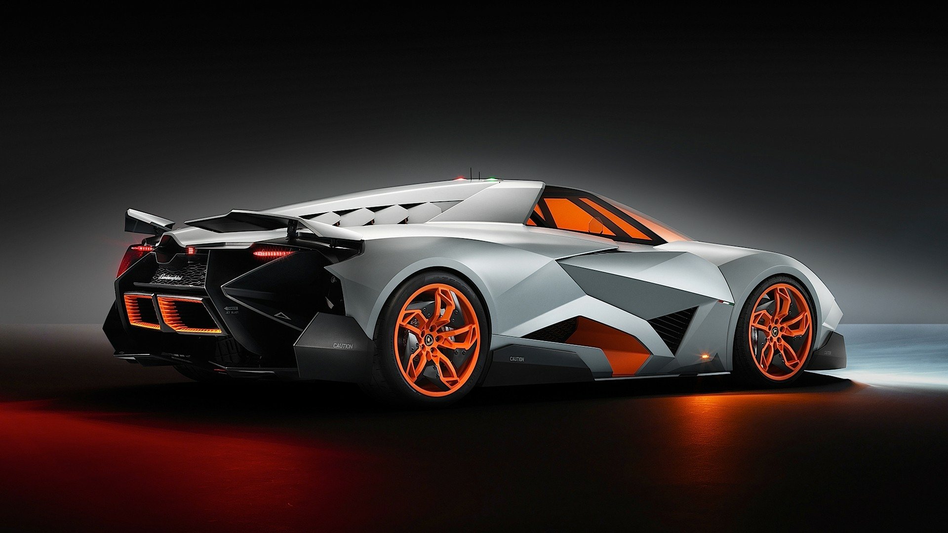 A sleek Lamborghini Egoista showcased in a dramatic lighting setup, featuring sharp angles and striking orange accents that highlight its futuristic design.