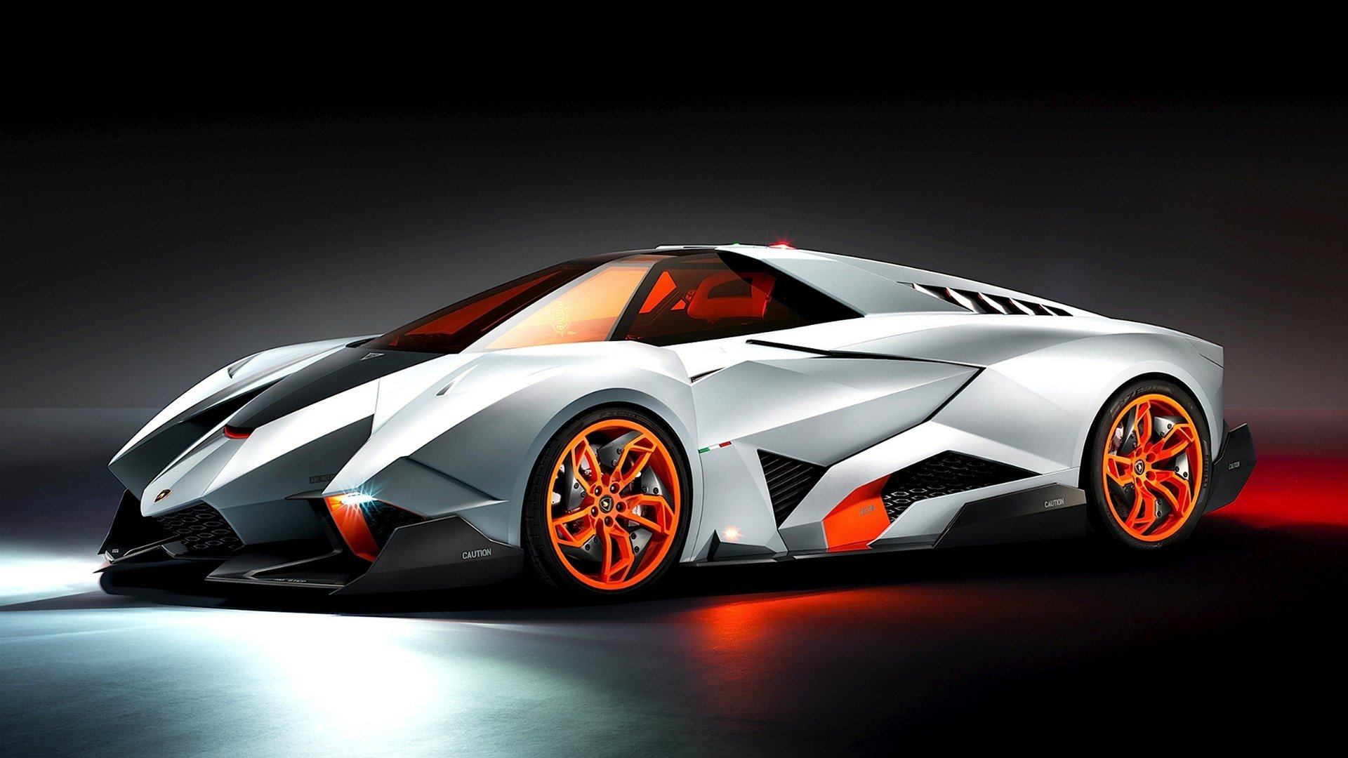 A sleek, futuristic Lamborghini Egoista with sharp angles, vibrant orange accents, and a low, aerodynamic profile showcased on a dark background.