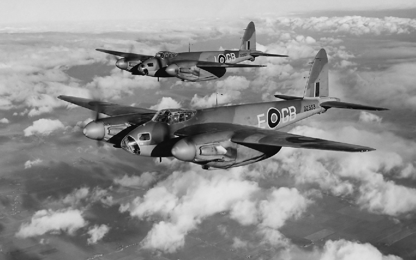 Two military aircraft flying in formation above the clouds, showcasing their distinctive design and sleek fuselage in a scenic black and white sky.