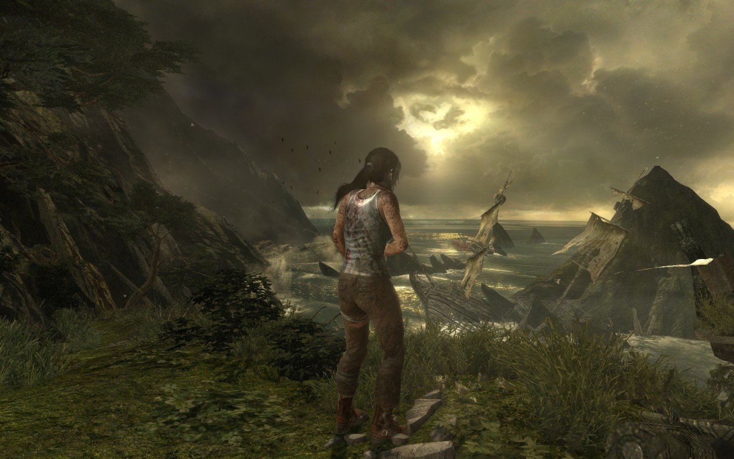 Lara Croft stands on a rugged cliff overlooking a stormy sea, with dark clouds and rocky formations in the background from the video game Tomb Raider.