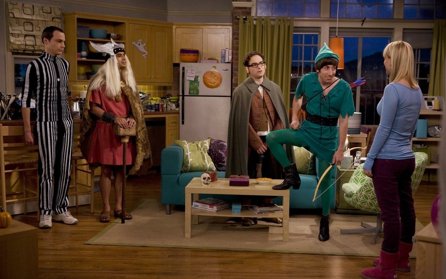 The Big Bang Theory cast, including Kaley Cuoco, Johnny Galecki, Jim Parsons, Simon Helberg, and Kunal Nayyar, dressed in costumes in the apartment set.