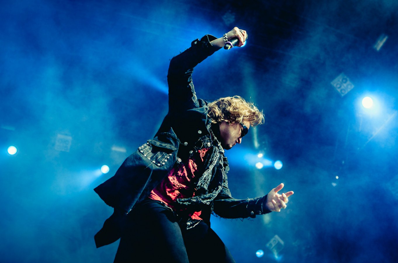 A dynamic live performance by Edguy’s lead singer, captured mid-song with vibrant blue stage lighting and energetic movement.