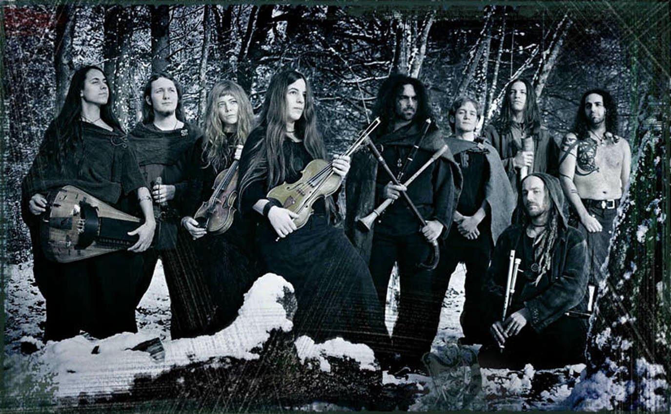 Eluveitie band members posed with traditional instruments in a forest setting, capturing the essence of their folk metal music style.