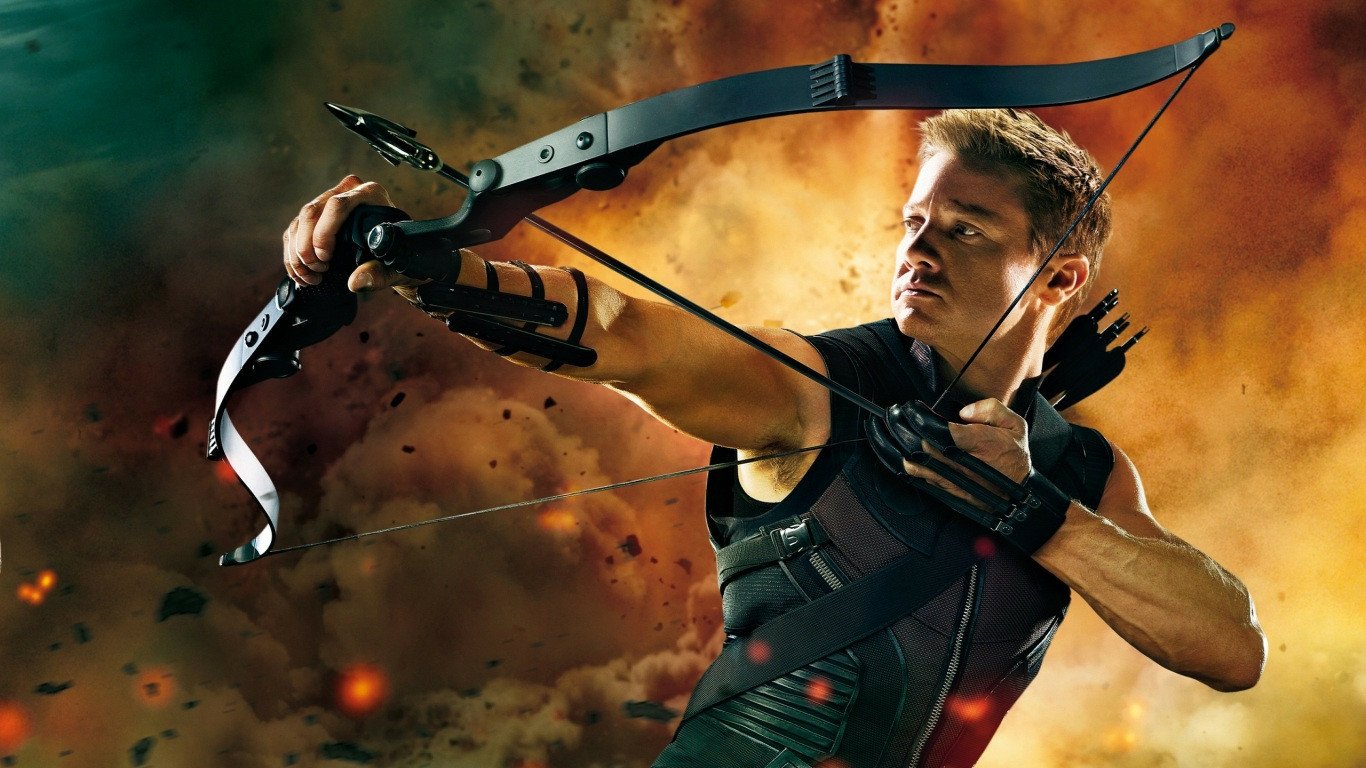 Jeremy Renner as Hawkeye draws his bow with determination, set against a dramatic explosion background from the Avengers movie.