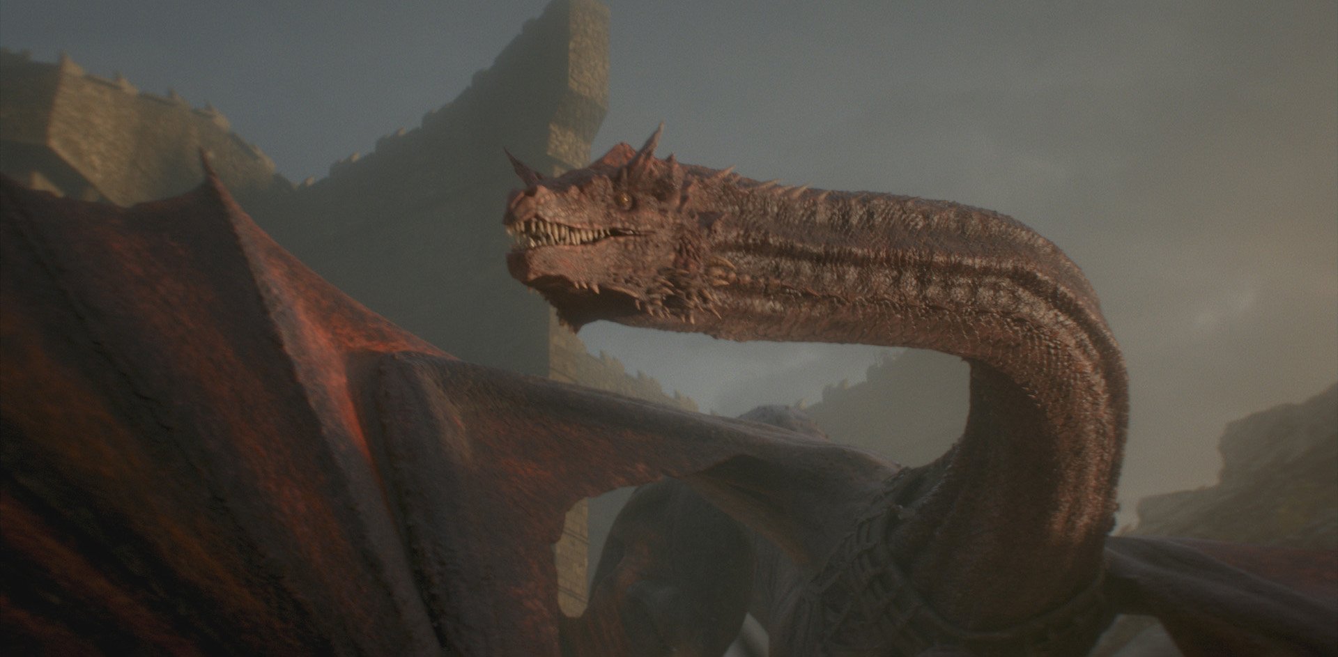 House of the Dragon (TV show): a massive dragon with a long, scaled neck and open jaws, leathery wings unfurled against a rocky, dusk-lit fortress backdrop.