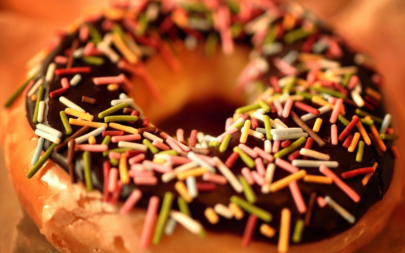 Close-up of a doughnut topped with chocolate glaze and colorful sprinkles, showcasing a classic sweet treat.