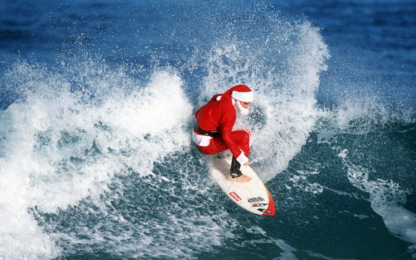 A person dressed as Santa Claus surfing on a wave, blending holiday cheer with an adventurous surfing scene.