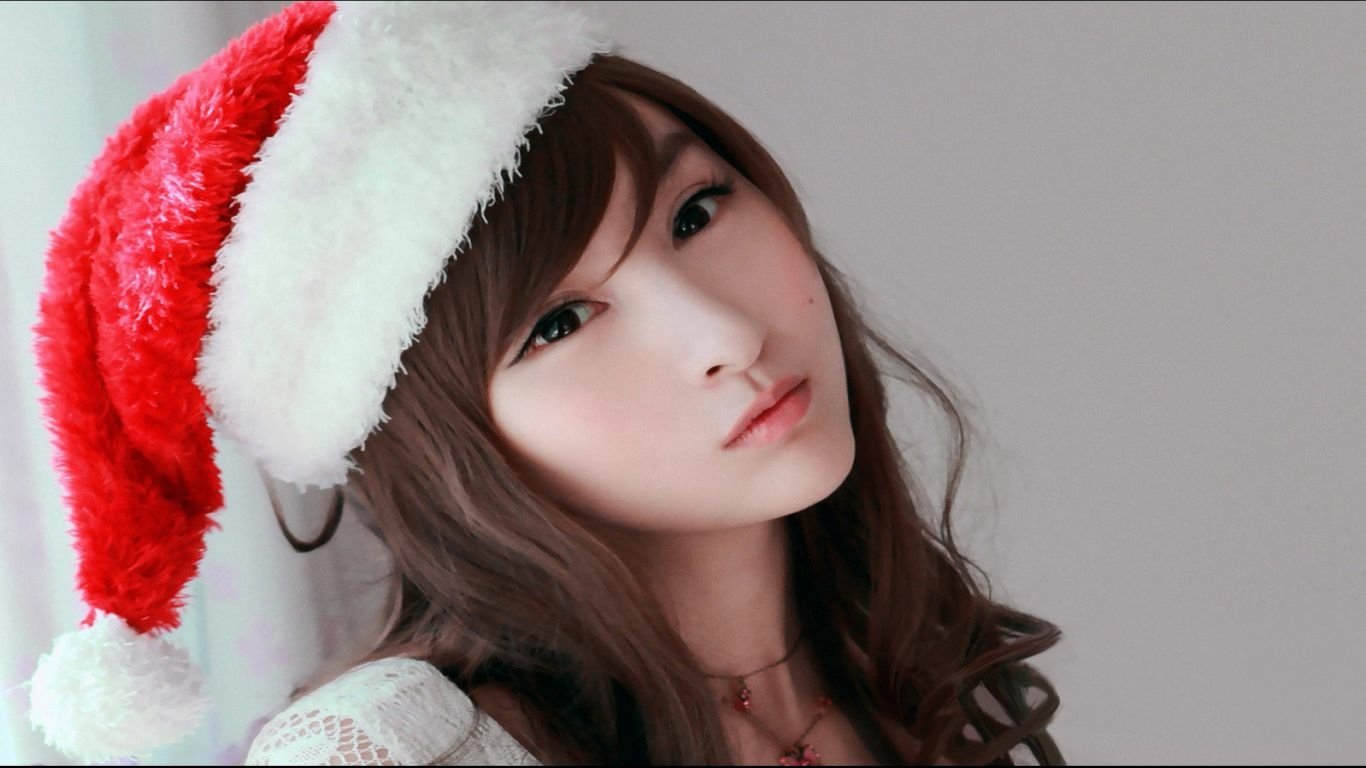 Portrait of Korean woman Lin Ketong wearing a red and white Santa hat against a plain background.