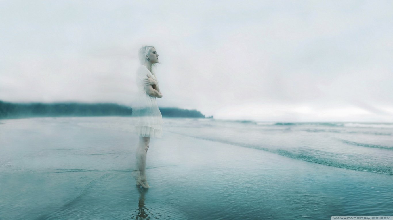 A ghostly figure stands in shallow water along a dark beach, shrouded in mist. The ethereal scene blends the mysterious with the serene, creating an otherworldly ambiance.
