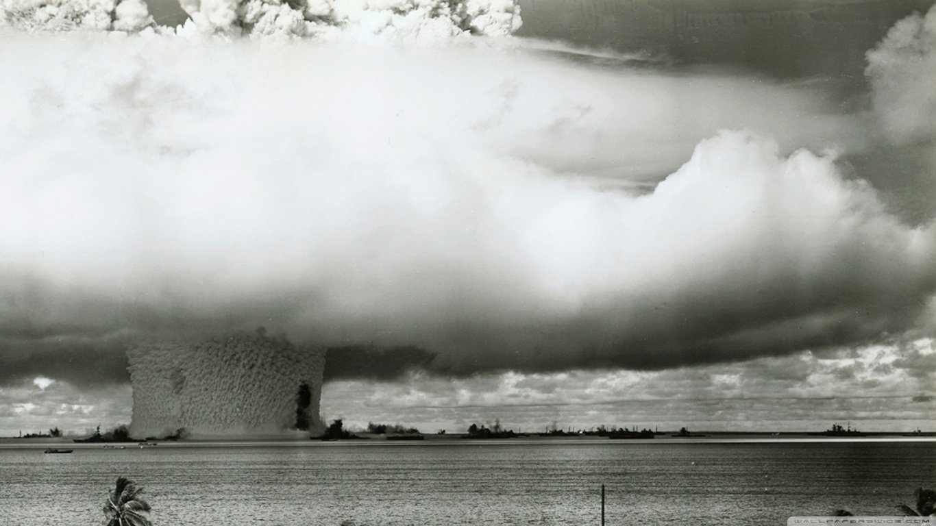 A dramatic black-and-white scene depicting a large explosion in a military context, with towering clouds rising into the sky over a flat landscape.