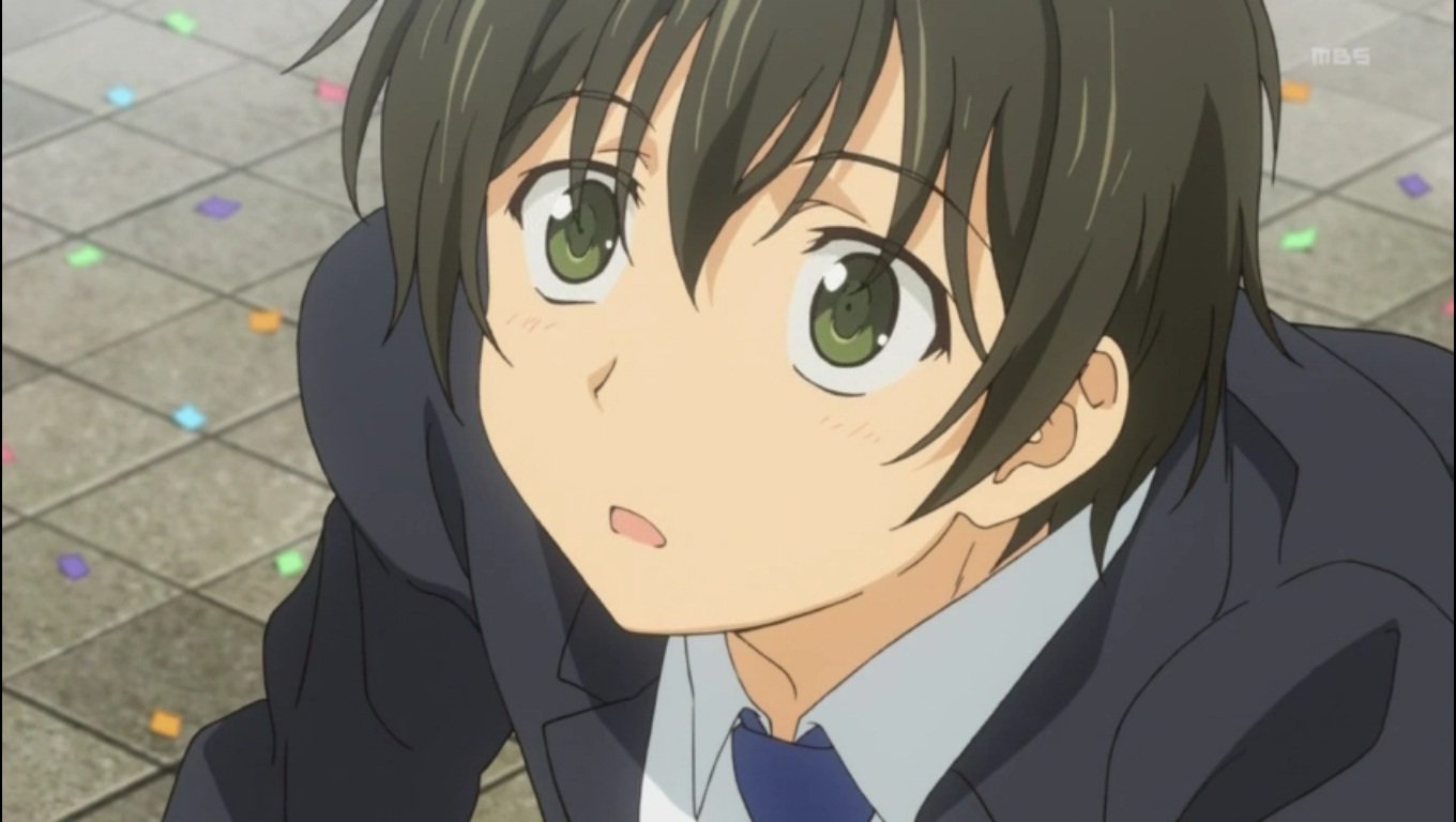 A close-up of Banri Tada from the anime Golden Time, looking upwards with wide green eyes, dressed in a dark suit against a background of colorful confetti on the ground.