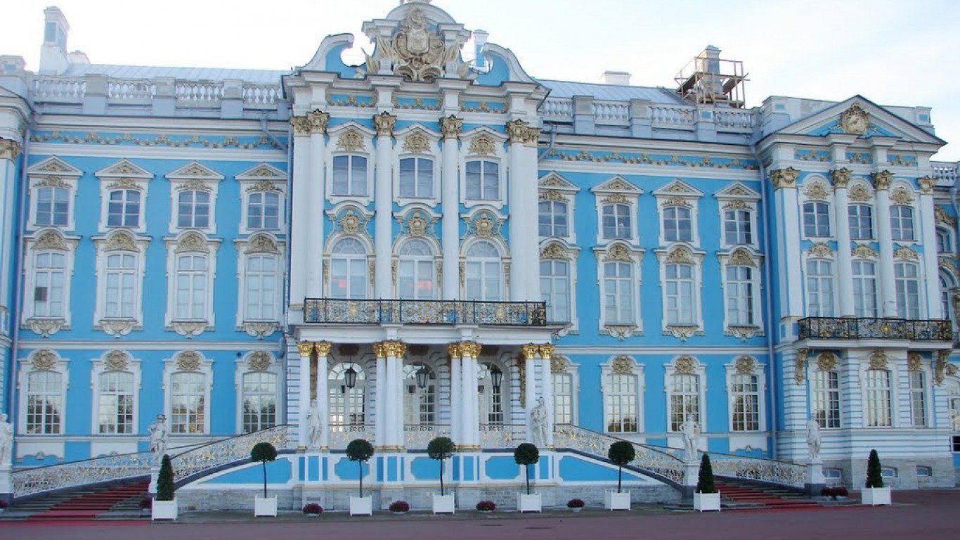 The Catherine Palace in Russia showcases ornate blue and white Baroque architecture with intricate gold accents on its grand façade.