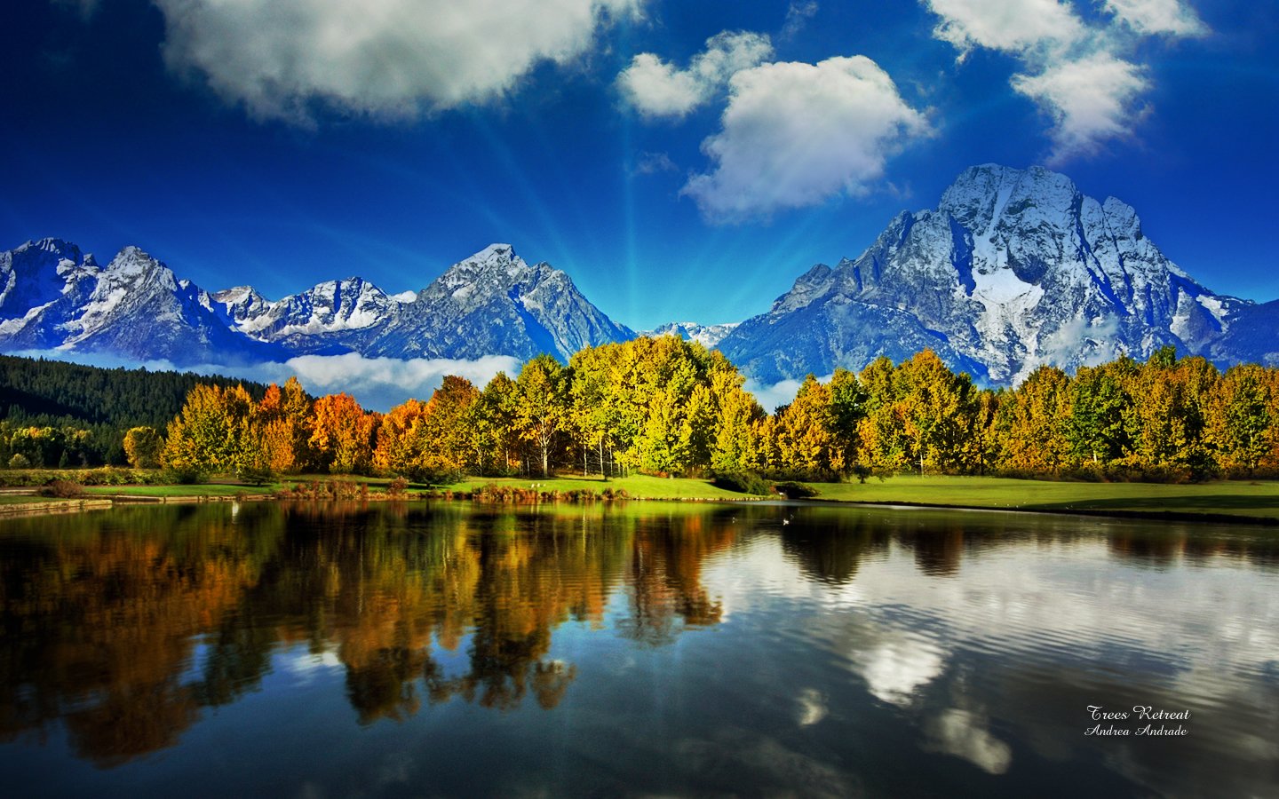 A serene lake reflecting colorful trees and towering mountains under a vibrant blue sky, showcasing a stunning nature landscape.
