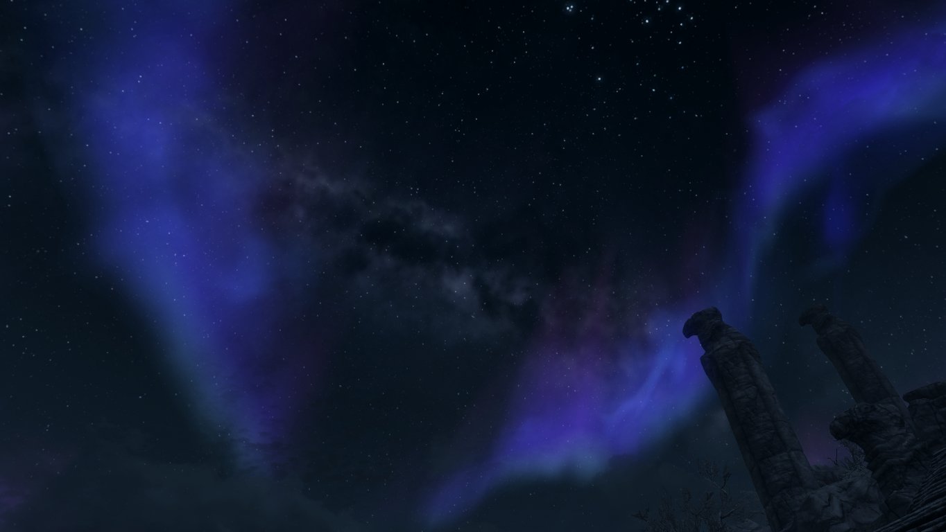 Night sky illuminated by vibrant blue and purple auroras over a mountainous landscape in the video game The Elder Scrolls V: Skyrim.
