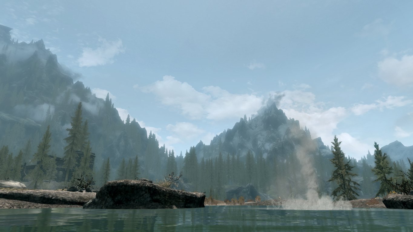 The Elder Scrolls V: Skyrim scene: misty mountains, tall pines and a calm river under a cloudy sky.