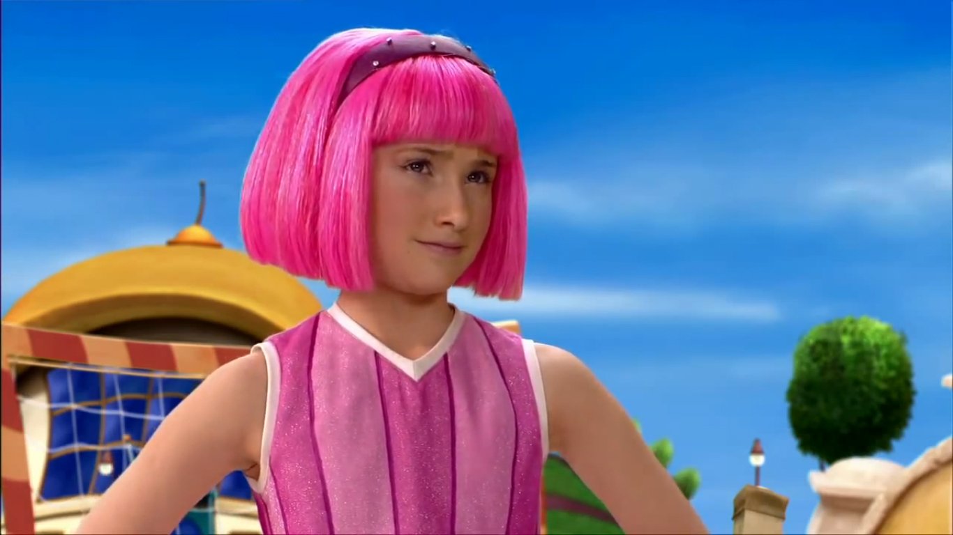 Stephanie from the TV show LazyTown, with a bright pink bob and sleeveless pink outfit, standing outdoors against a colorful playset and blue sky.