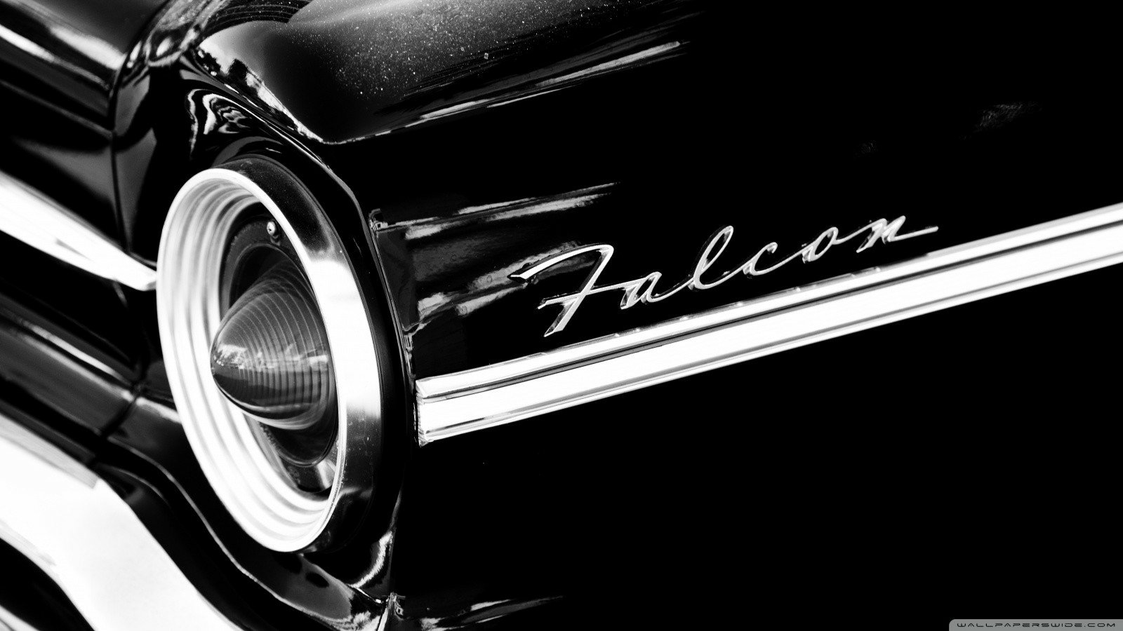 Black-and-white close-up of a Ford Falcon vehicle's front end, highlighting a round headlight, chrome trim and cursive Falcon emblem.