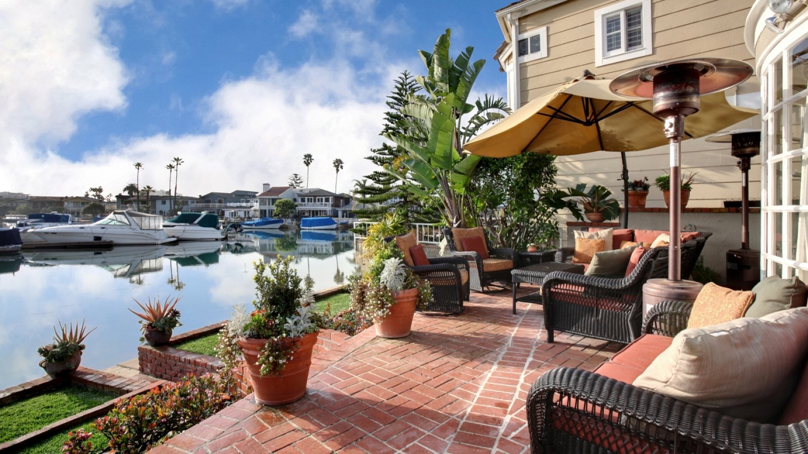 A man-made room with a spacious outdoor patio overlooking a marina filled with boats under a bright blue sky.