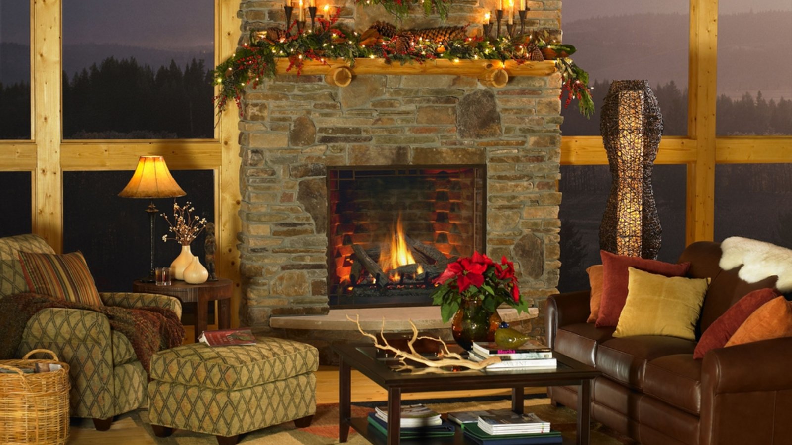 Cozy living room with a stone fireplace decorated with Christmas ornaments and holiday greenery, surrounded by comfortable seating and warm lighting.