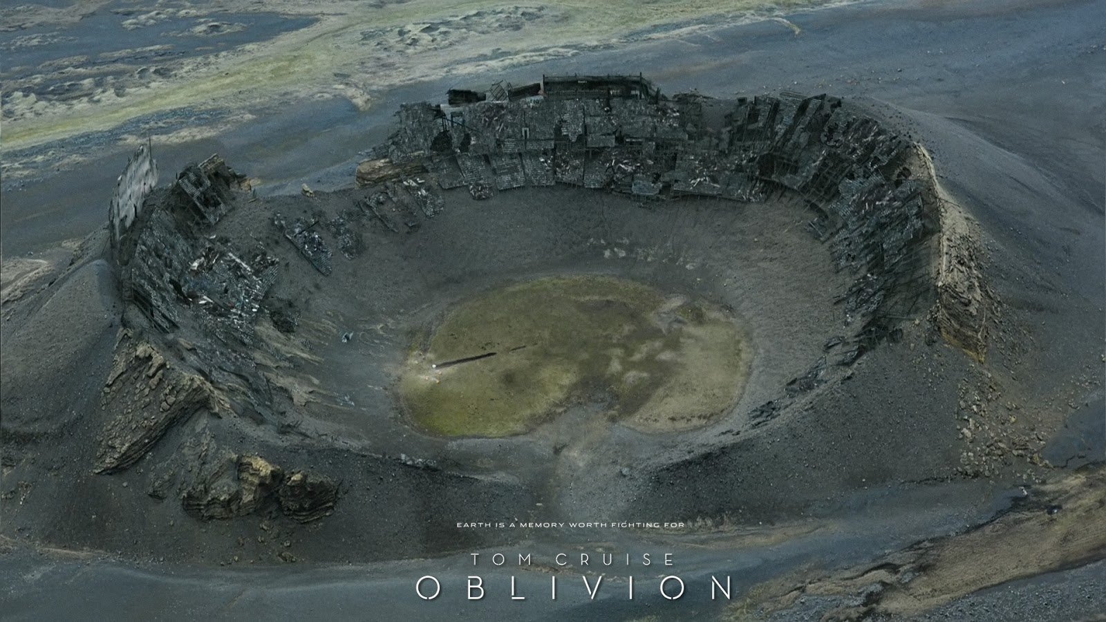 A large, circular crater in a barren landscape from the movie Oblivion (2013), featuring rugged terrain and a muted color palette.