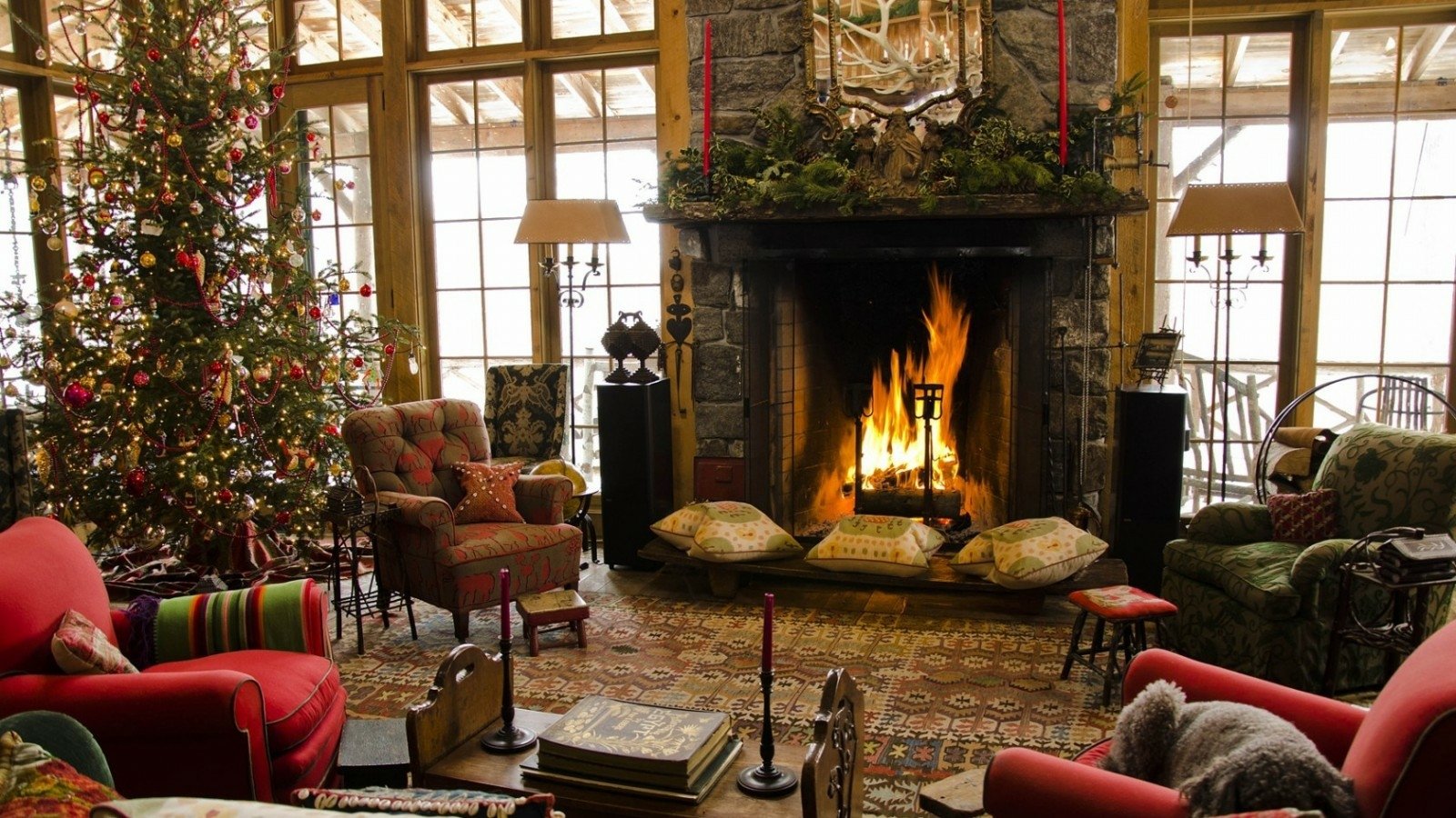 Cozy living room decorated for Christmas with a tree adorned in ornaments, a roaring fireplace, and comfortable seating arranged for holiday gatherings.