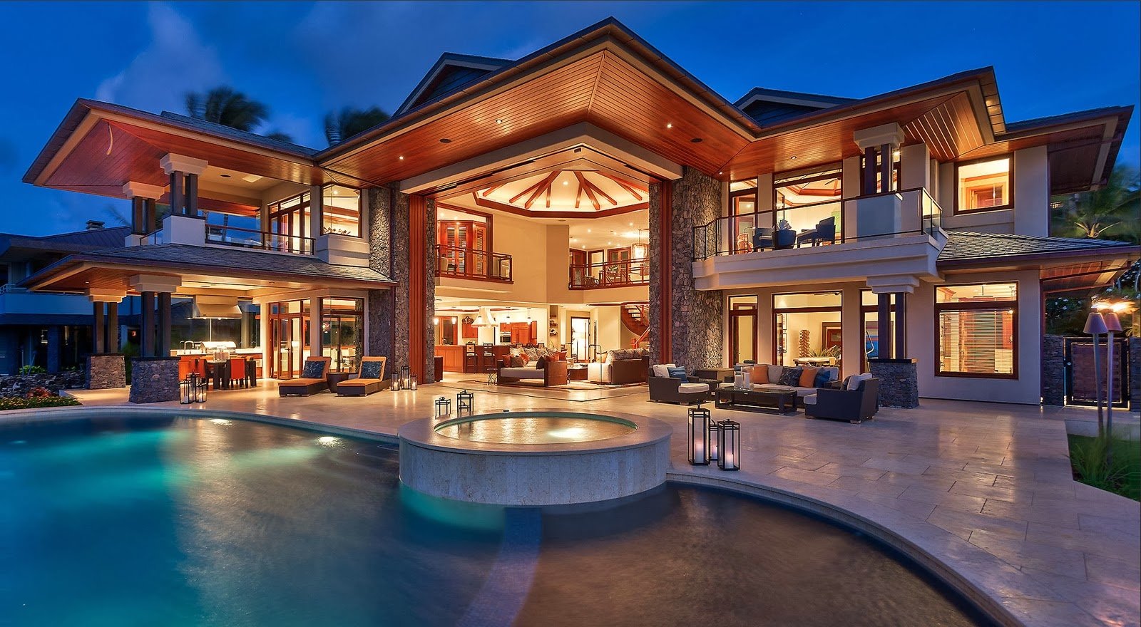 A stunning man-made house featuring a spacious patio and a shimmering pool, illuminated at night, showcasing modern architecture and a serene outdoor environment.
