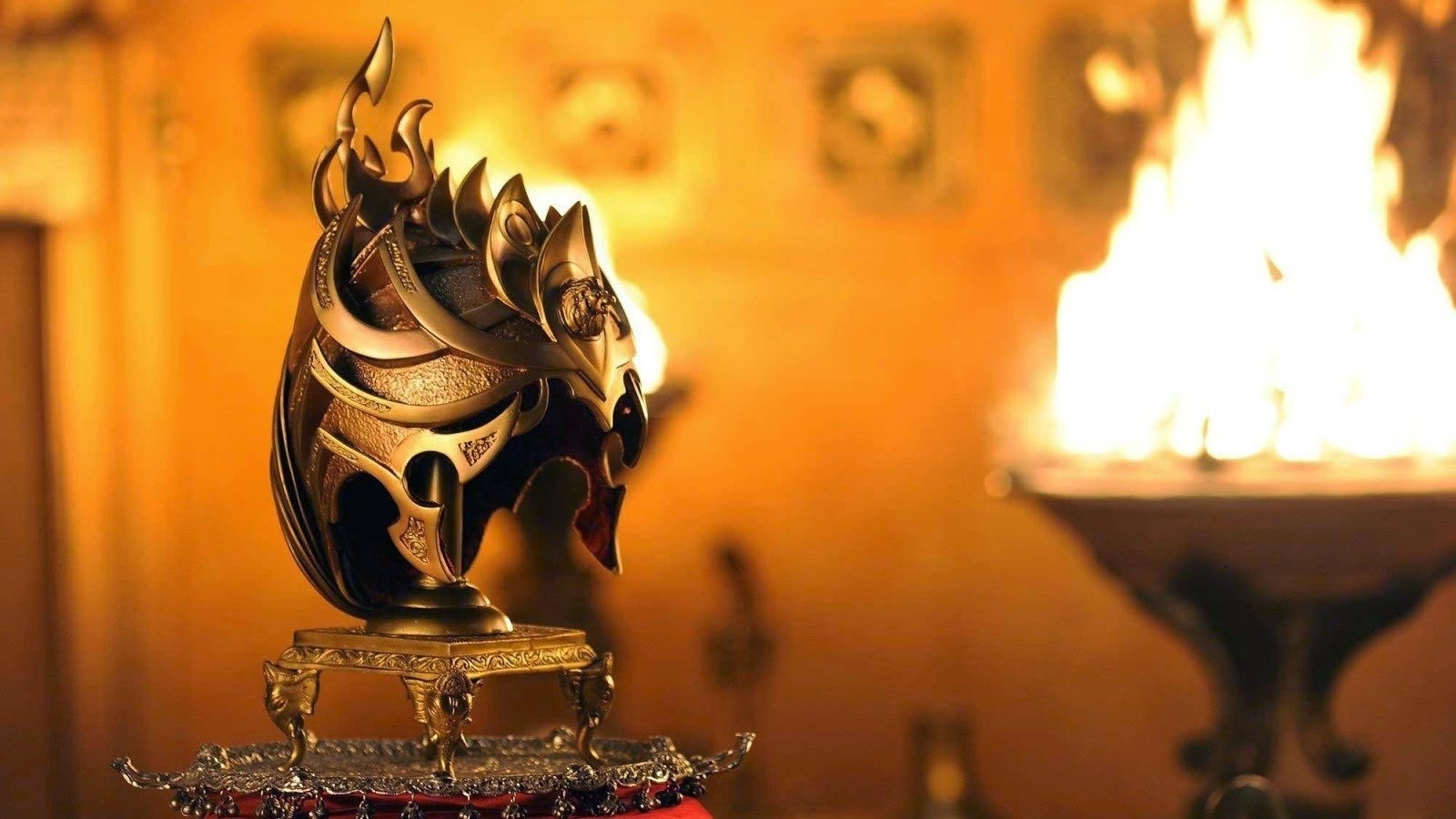 A detailed warrior helmet displayed on a stand with warm lighting and a fire burning in the background, from the movie Baahubali: The Beginning.