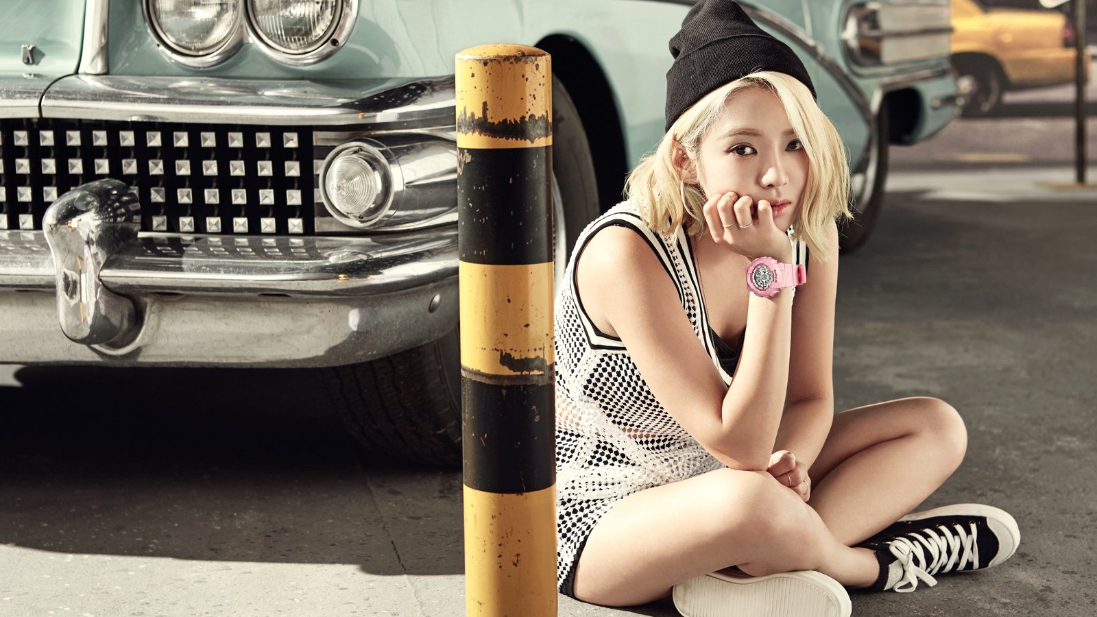 Young woman in sporty outfit and beanie sits by a vintage car, pop music aesthetic inspired by Girls' Generation (SNSD).