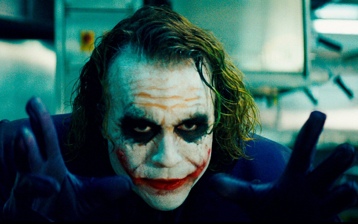 Heath Ledger as the Joker in *The Dark Knight*, captured with dramatic makeup, intense expression, and menacing hands, embodying the character's chaotic nature.