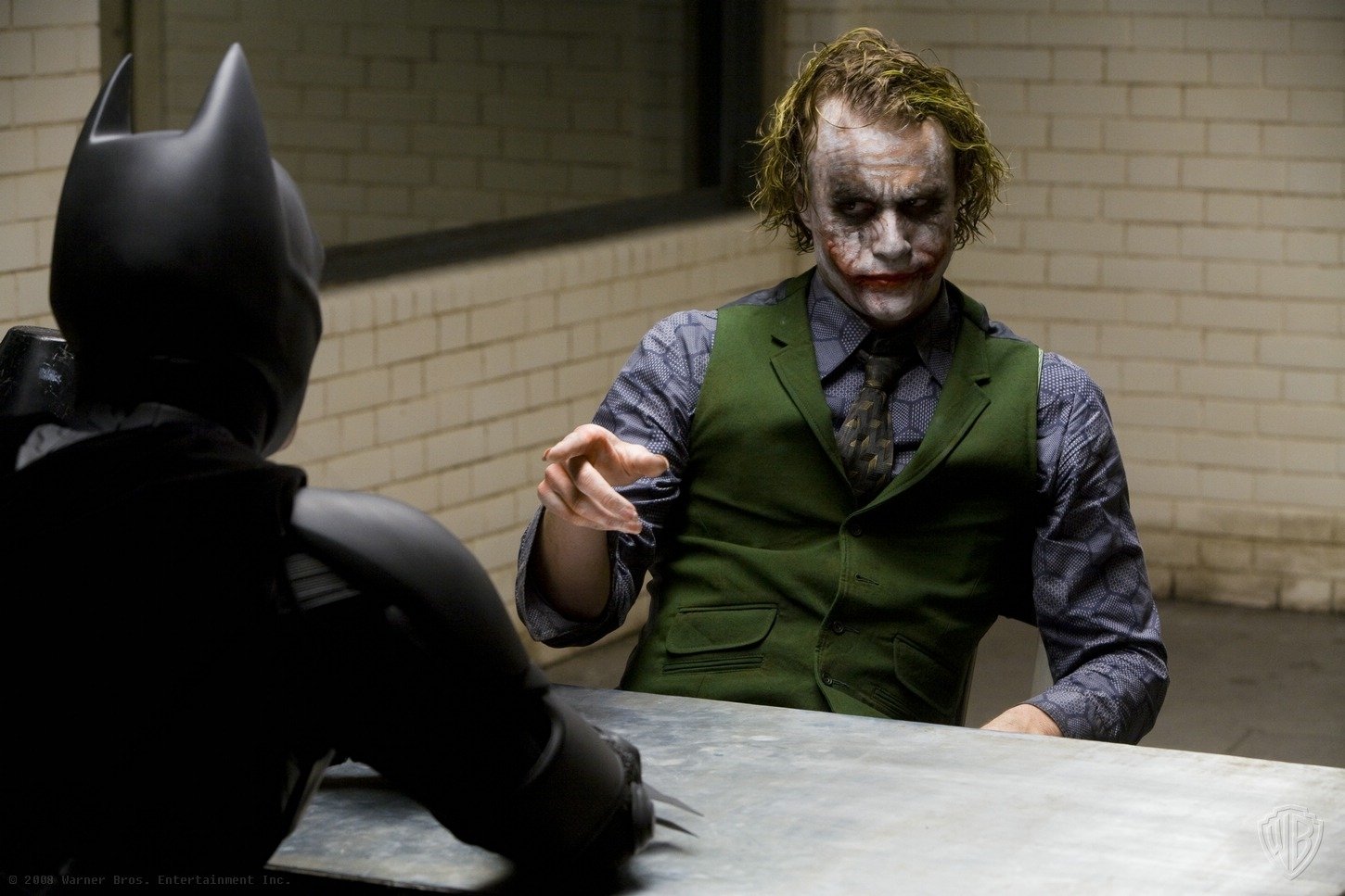 Batman faces the Joker, portrayed by Heath Ledger, during a tense interrogation scene from the movie The Dark Knight. The setting is stark and intense, reflecting their intricate dynamic.