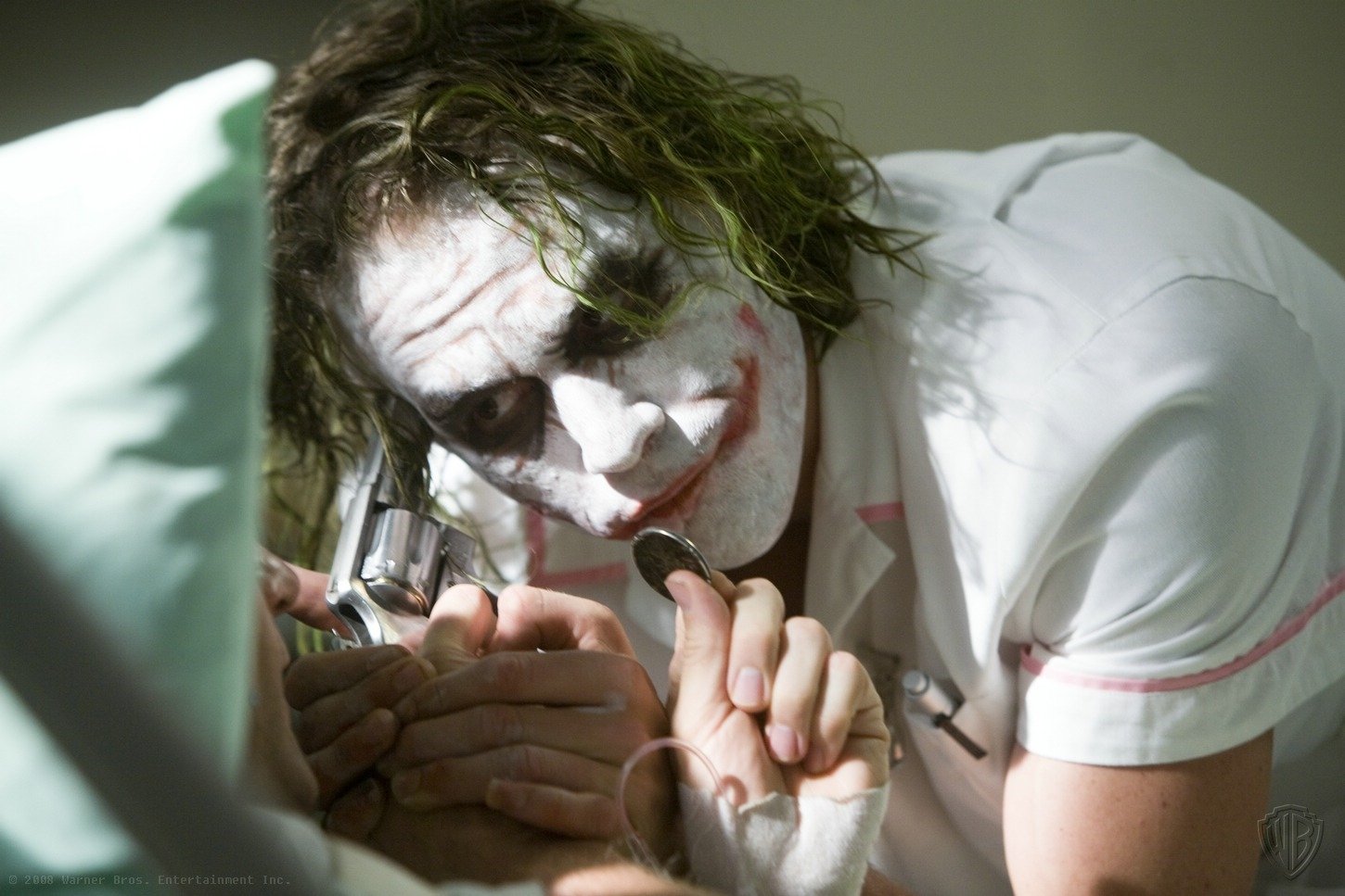 Heath Ledger's iconic portrayal of the Joker in *The Dark Knight* captures a tense moment, with the character menacingly holding a gun while interacting with a victim.