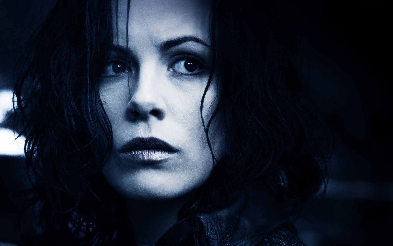 A close-up of Kate Beckinsale in a dramatic pose from the movie Underworld: Evolution, featuring her intense expression against a dark blue backdrop.