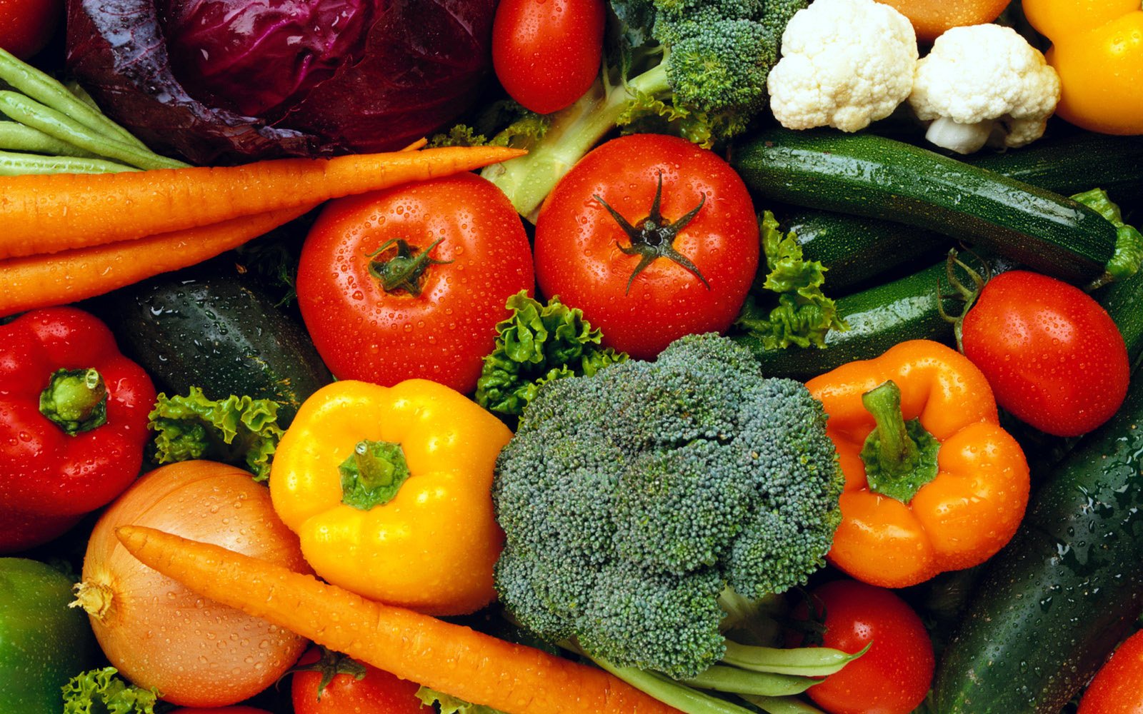 A vibrant assortment of fresh vegetables, including tomatoes, peppers, carrots, broccoli, and lettuces, arranged beautifully for a colorful display.