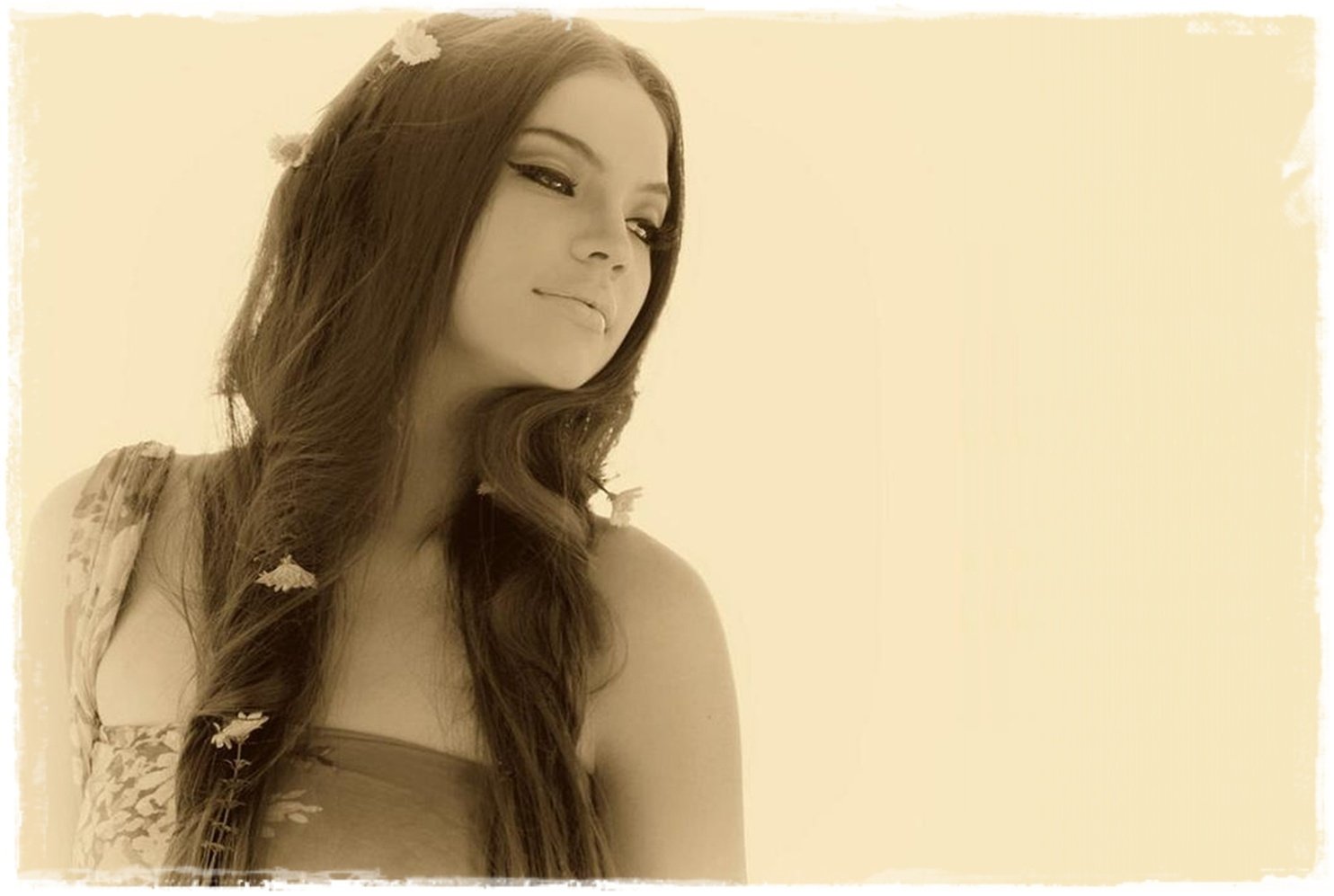 Sepia-toned portrait of celebrity Rhian Ramos with long flowing hair adorned with small flowers, gazing thoughtfully to the side.