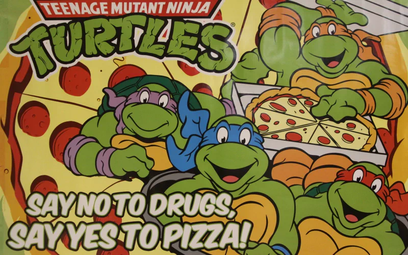 Colorful comic artwork featuring the Teenage Mutant Ninja Turtles—Raphael, Donatello, Leonardo, and Michelangelo—celebrating pizza with a message against drugs.