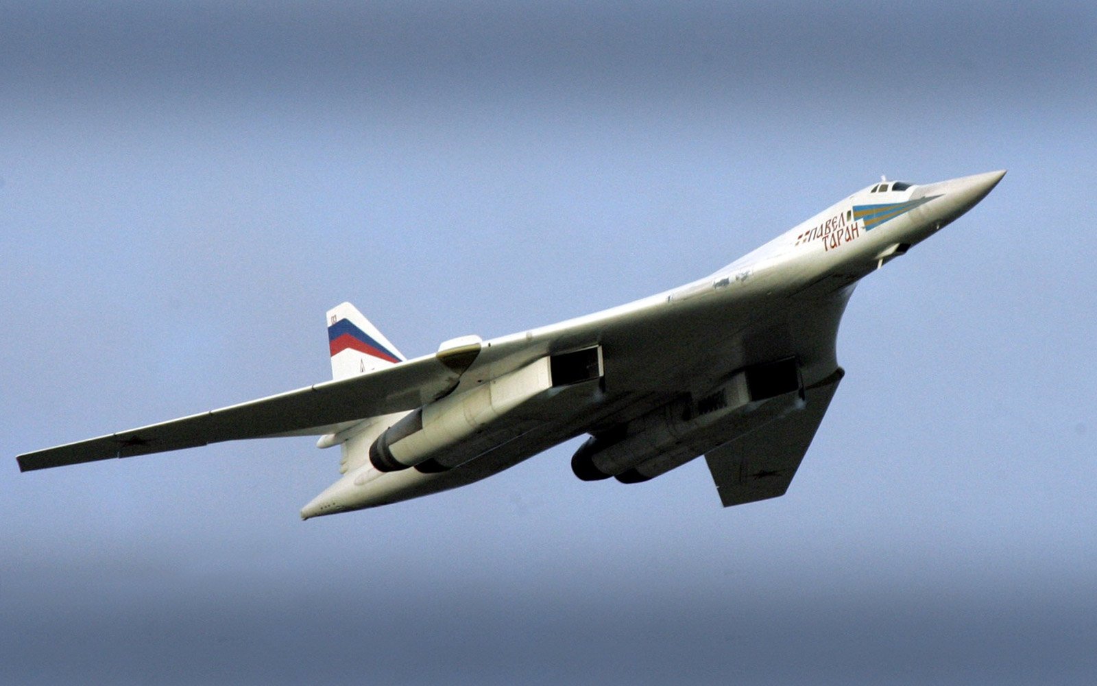 A military Tupolev Tu-160 supersonic strategic bomber in flight against a clear sky.