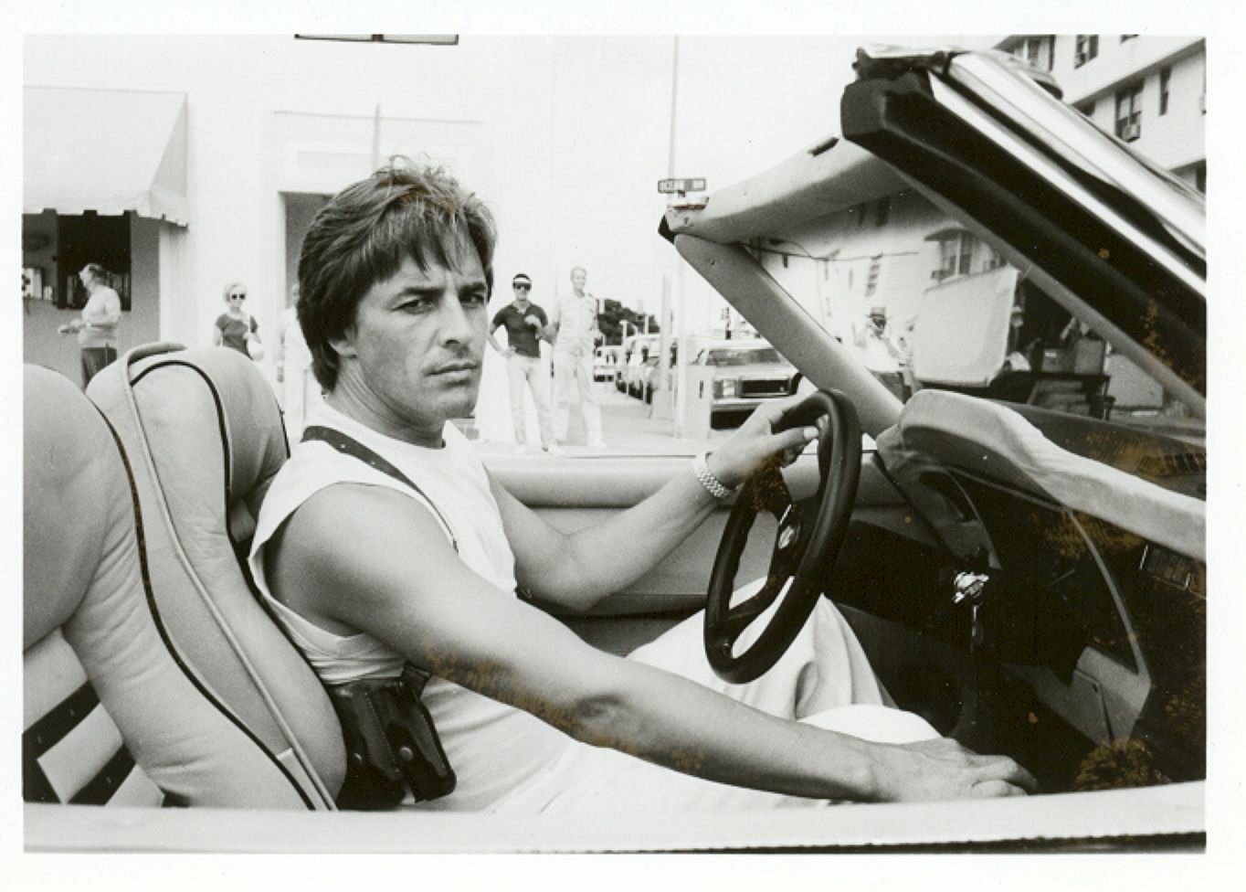 Black-and-white image of a man in a convertible car, capturing a scene from the TV show Miami Vice.