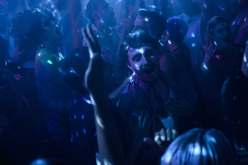 Vibrant club scene with party-goers from the movie 'All of Us Are Strangers' enjoying the night.