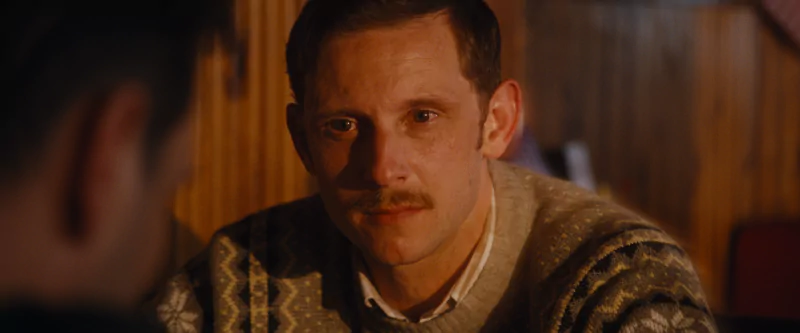 Intense scene from All of Us Are Strangers movie showing a man with a contemplative expression wearing a patterned sweater.