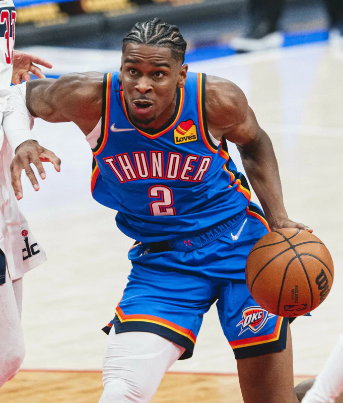 Oklahoma City Thunder player in action during an NBA basketball game, dribbling past an opponent.