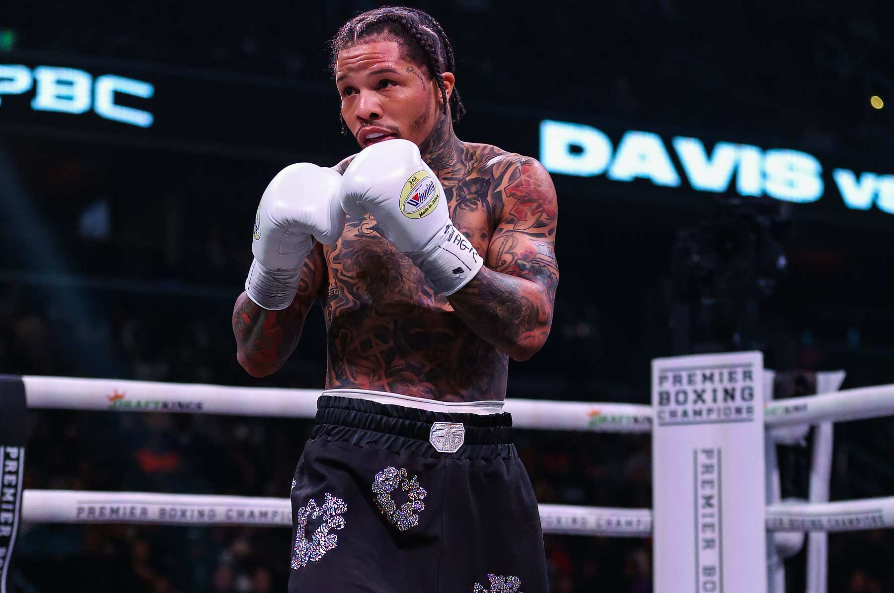A boxer in a ring wearing gloves and trunks, ready to fight, with tattoos visible on his arms and chest. Text on the image includes PBC and DAVIS vs.