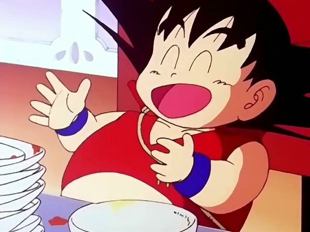 A delighted young Goku from Dragon Ball laughs with a satisfied expression, surrounded by empty plates, suggesting he's just finished a big meal.