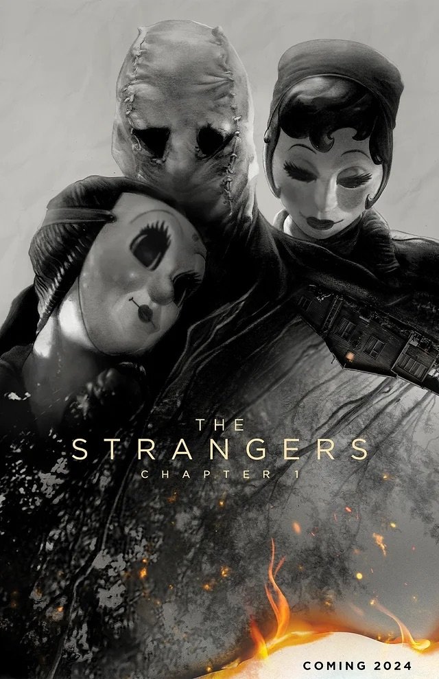 Three masked figures ominously pose against a dark backdrop in the promotional poster for the horror movie The Strangers: Chapter 1, slated for release in 2024. Fire burns at the bottom.
