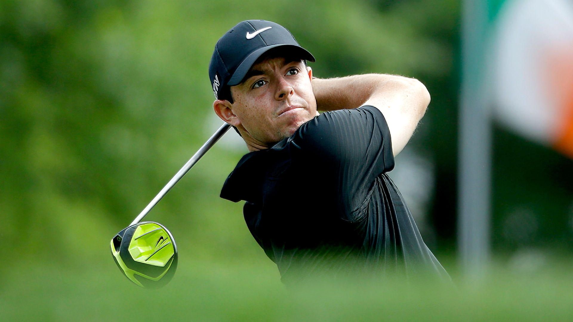 A golfer, tagged as Rory McIlroy, swings his club on a lush golf course under a clear sky, embodying the spirit of sports and golf.