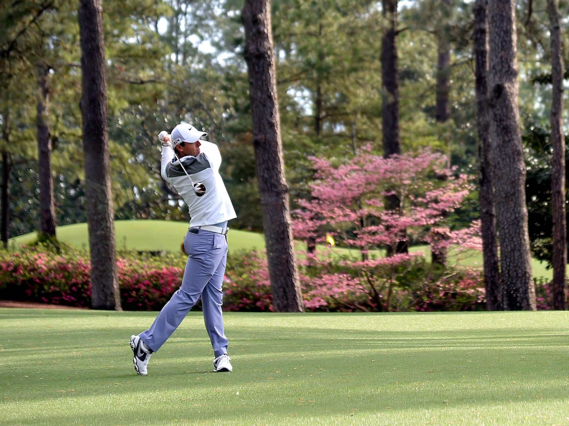 A golfer prepares to swing on a golf course. The image is related to sports and features Rory McIlroy.