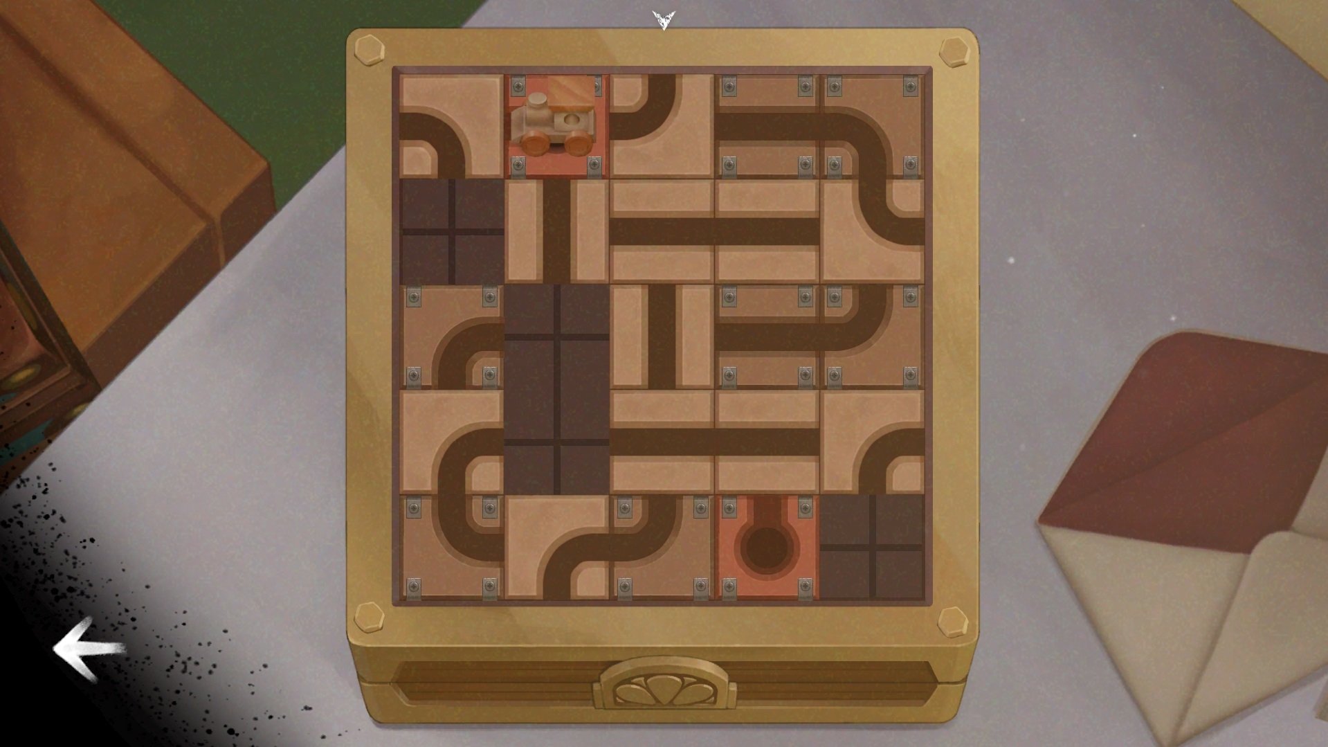 A wooden puzzle board featuring interconnected pathways, part of the video game The Star Named EOS, laid on a table beside envelopes.