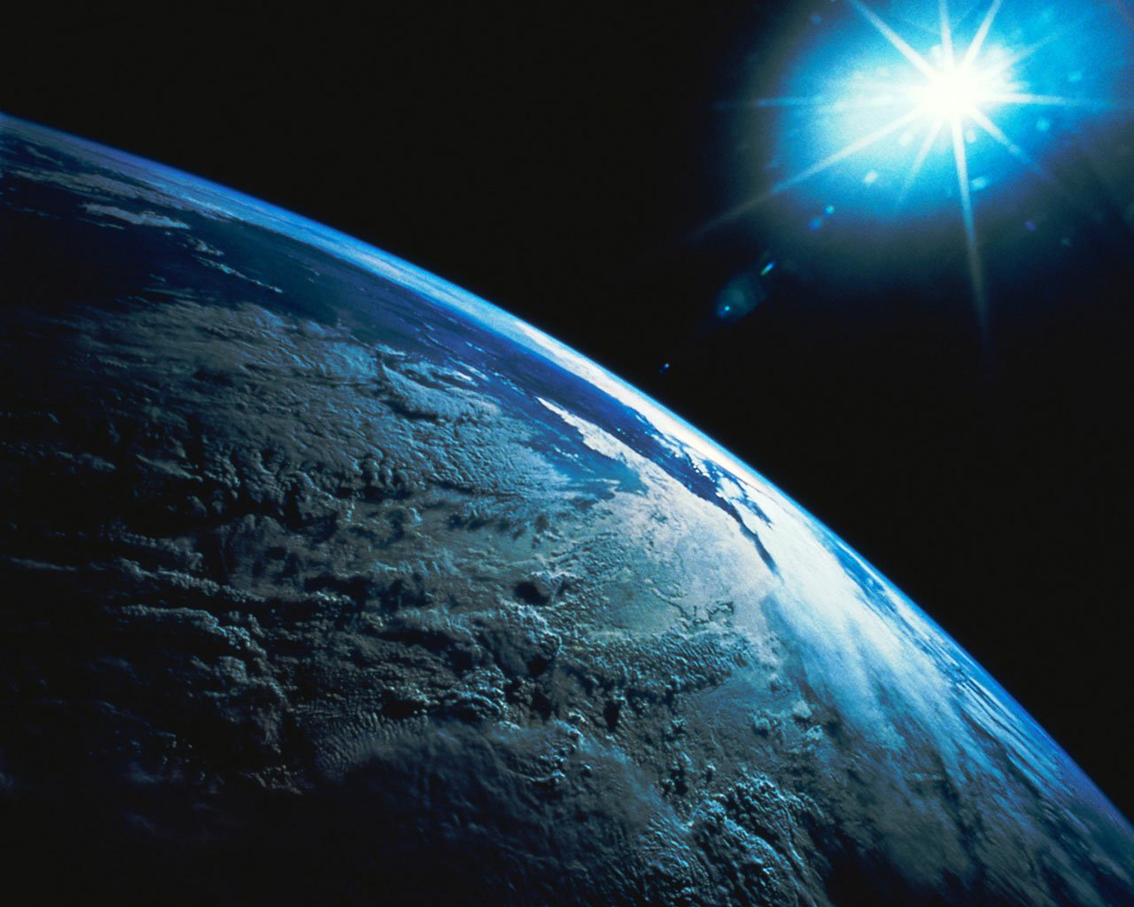 View of Earth from space with the sun shining brightly in the background.