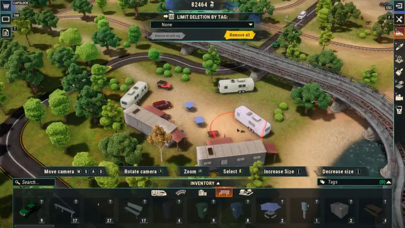 An aerial view of a customized train yard in the video game Train Yard Builder, featuring various vehicles, structures, and lush greenery. Tools for editing are visible at the bottom.