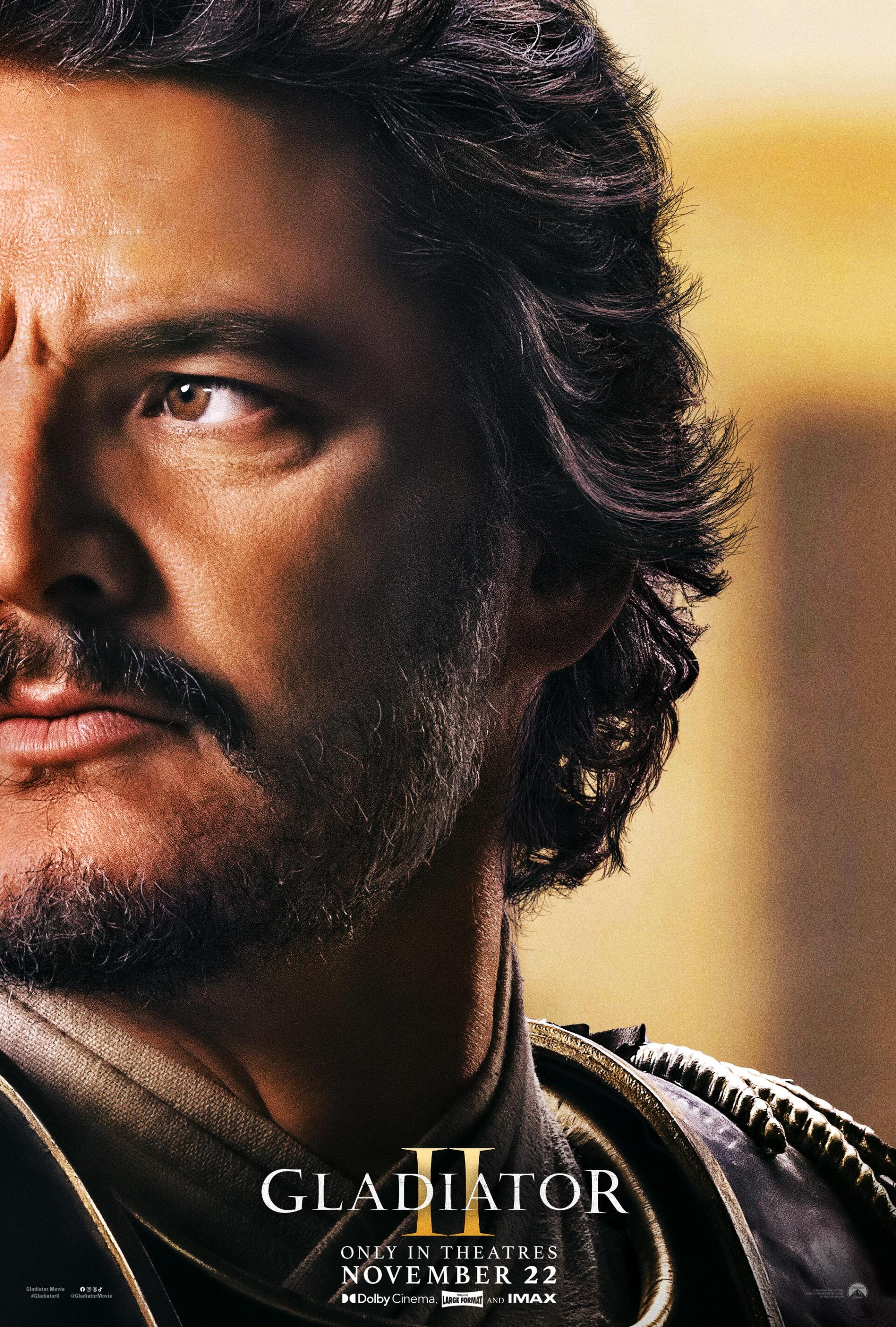 A close-up of Pedro Pascal in a promotional image for Gladiator II, showcasing his intense expression against a blurred background. The film releases in theaters on November 22.