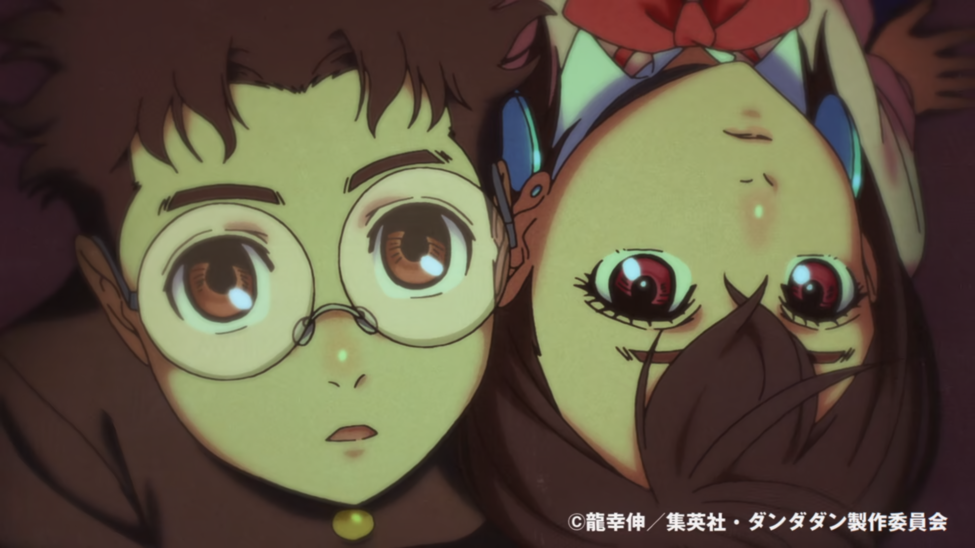 Close-up of two characters from Dandadan, one wearing glasses and the other with large eyes, lying down and looking directly at the viewer, featuring Ken Takakura and Momo Ayase influences.